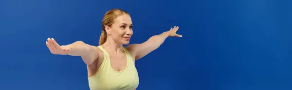 A focused woman in a crop top is performing an exercise with arms extended, embodying fitness and energy. — Stock Photo