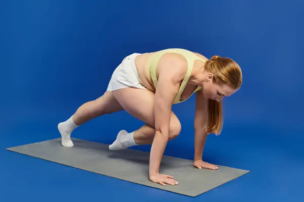 A dedicated sportswoman performs a dynamic exercise routine in a vibrant studio setting. — Stock Photo