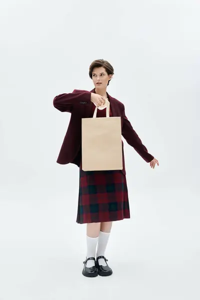 Eine stilvolle Frau in eleganter Winterkleidung hält eine Einkaufstasche in der Hand, die gemütlichen Charme und Wärme ausstrahlt. — Stockfoto
