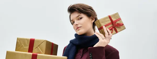 Wrapped in cozy elegance, a woman displays her festive spirit by showcasing seasonal gifts. — Stock Photo