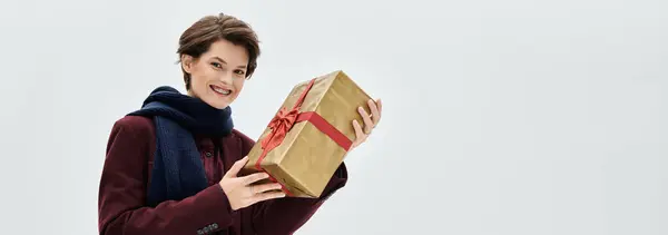 Eine stilvolle Frau in eleganter Winterkleidung trägt ein festliches Geschenk in der Hand. — Stockfoto