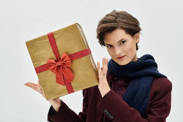 A stylish woman in warm winter attire embraces the holiday spirit with a beautifully wrapped gift. — Stock Photo