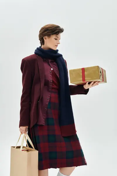 A stylish woman in winter attire contemplates a beautifully wrapped gift while dressed elegantly. — Stock Photo