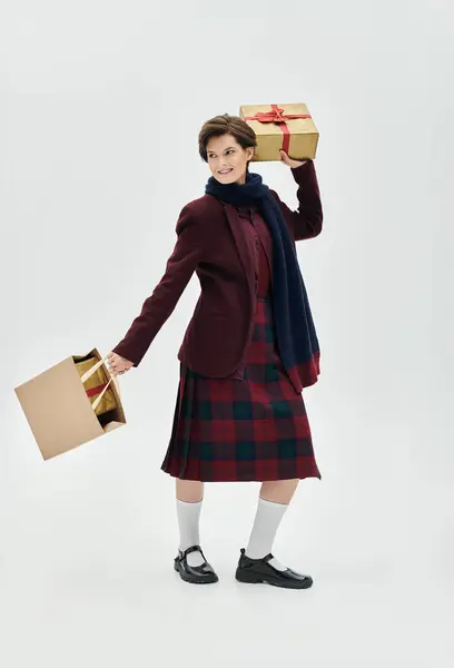 A cheerful woman dressed elegantly for winter holds festive gifts, exuding warmth and joy. — Stock Photo