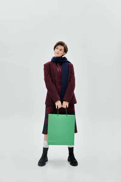 The cozy clad woman stands confidently, holding a vibrant green bag, exuding winter charm. — Stock Photo