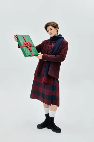 With a warm smile, a woman dressed in elegant winter attire showcases a beautifully wrapped gift. — Stock Photo