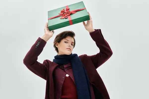 A beautifully dressed woman showcases a wrapped gift, exuding warmth and style in winter attire. — Stock Photo