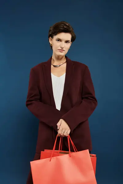 A poised woman in stylish winter attire confidently carries vibrant shopping bags. — Stock Photo