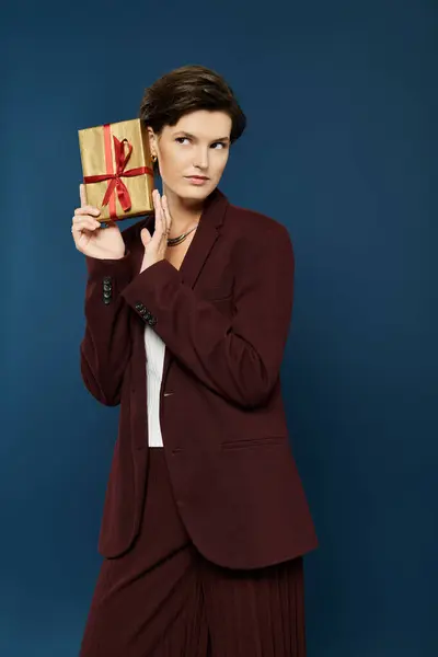A chic woman in cozy winter attire presents a beautifully wrapped gift with confidence. — Stock Photo
