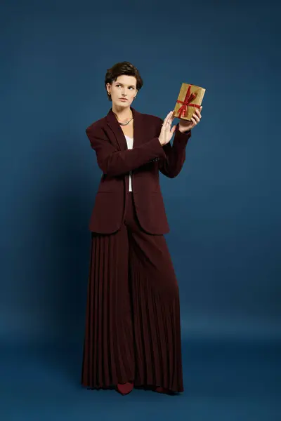 A fashionable woman showcases an elegantly wrapped present while dressed in cozy winter layers. — Stock Photo