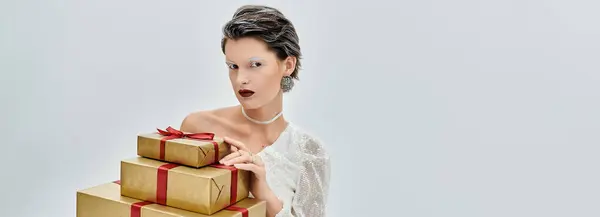 A stylish woman stands gracefully with festive gifts in a cozy winter setting. — Stock Photo