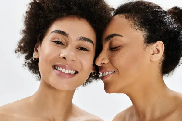 Two women share joyful smiles in a brightly lit space, highlighting their close friendship. — Stock Photo