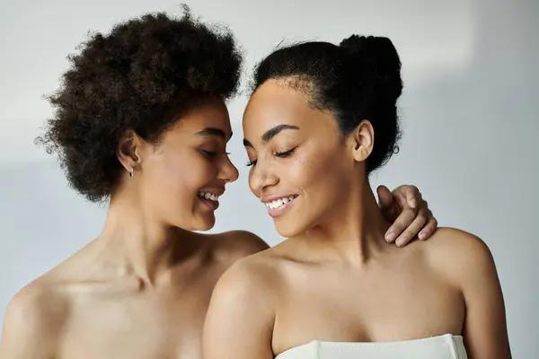 Two women lean close, smiling warmly at each other in a serene, softly lit environment. — Stock Photo