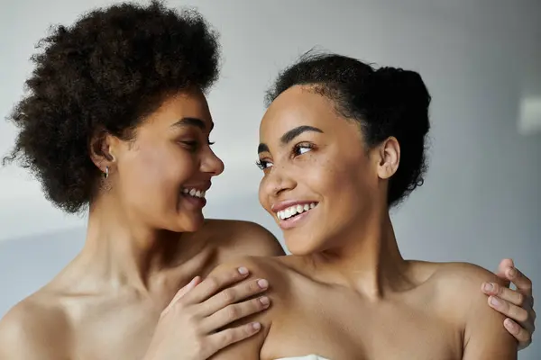 Two friends embrace joyfully, their expressions radiating warmth and happiness in a cozy atmosphere. — Stock Photo