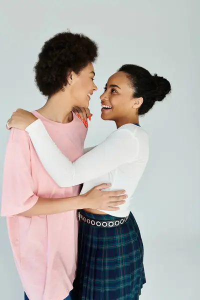 Two friends embrace and smile at each other, radiating happiness and connection in a bright space. — Stock Photo