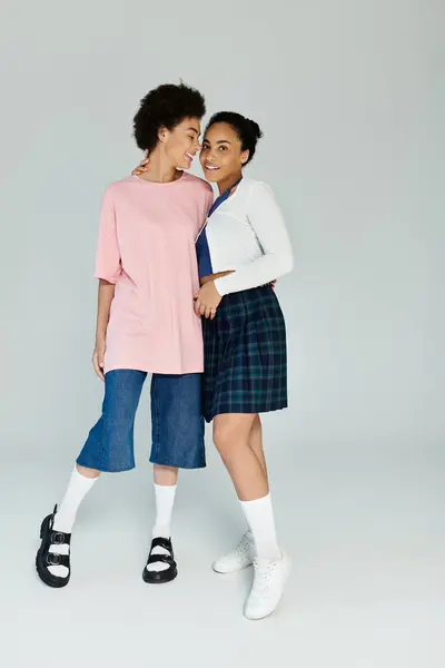 Two friends stand closely together, smiling and enjoying each others company in trendy attire. — Stock Photo