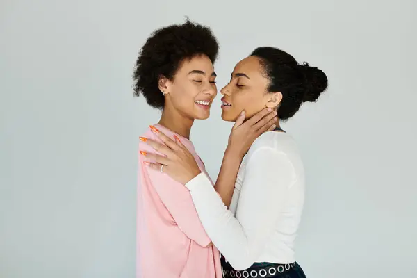 Two friends embrace in a tender moment, sharing smiles and joy in a minimalist setting. — Stock Photo