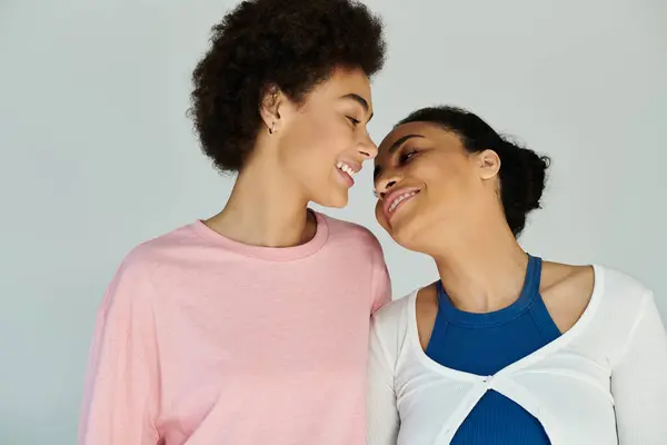 Two women lean close together, exchanging joy filled smiles in a bright atmosphere. — Stock Photo