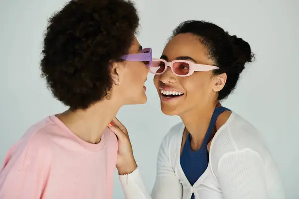 Two friends engage in a playful moment, exchanging colorful eyewear with smiles and laughter. — Stock Photo