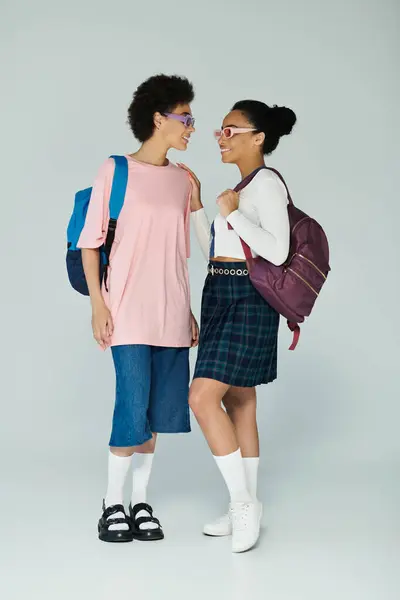 Dois amigos alegres estão perto, mostrando suas roupas da moda e expressões lúdicas. — Fotografia de Stock