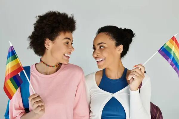 Two friends joyfully share a moment together, proudly waving rainbow flags in celebration. — Stock Photo