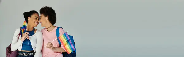 Due amici abbracciano la diversità, portando con orgoglio bandiere arcobaleno in un momento sincero. — Foto stock