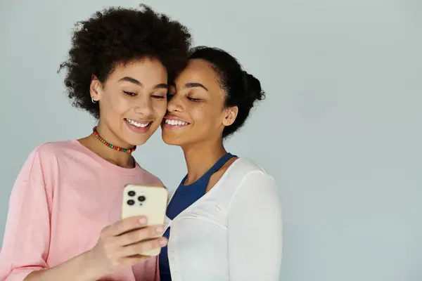 Deux jeunes femmes partagent un moment de rire et de connexion en utilisant un smartphone. — Photo de stock