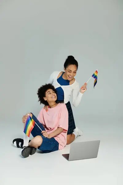 A vibrant celebration of friendship as two individuals share a moment of joy with pride flags. — Stock Photo