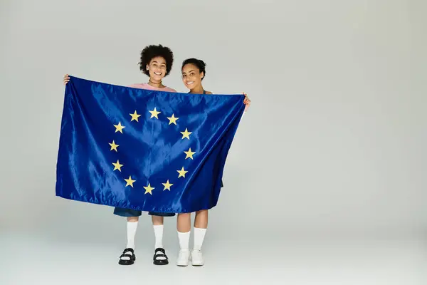 Dois jovens sorriem alegremente enquanto exibem a bandeira europeia juntos. — Fotografia de Stock