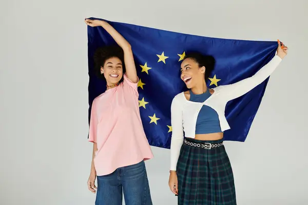 Two friends express happiness while proudly displaying the European Union flag together. — Stock Photo