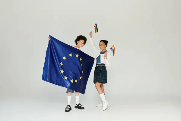 Zwei Personen zeigen stolz die EU- und Regenbogenfahnen und feiern Einheit und Vielfalt. — Stockfoto