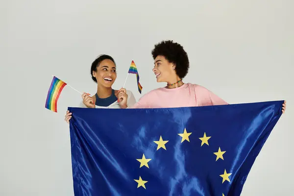 Two friends proudly display the European and Pride flags, celebrating inclusivity and joy. — Stock Photo