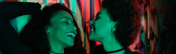 Two friends share laughter and joy in a colorful setting, embodying friendship and happiness. — Stock Photo