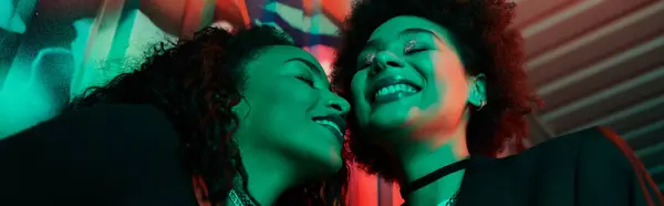 Two friends share a heartfelt laugh in a colorful, artistic environment filled with vibrant hues. — Stock Photo