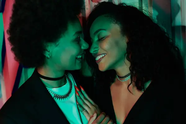 Two friends share a joyful moment, their faces illuminated by colorful lights, radiating happiness. — Stock Photo