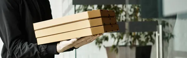 A delivery professional brings stacked packages to a bustling office building. — Stock Photo