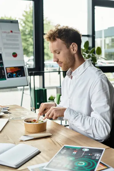 Handsome and redhead man in white shirt eating tasty salad in modern office — Stock Photo