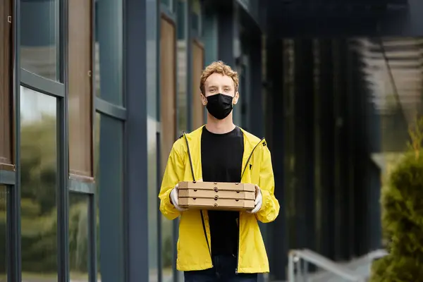 A delivery man in a black mask arrives at an office building, carrying several pizza boxes for lunch. — Stock Photo