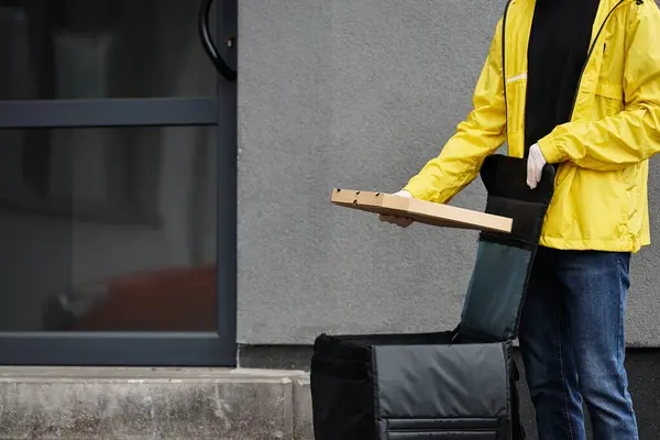 Um homem de entrega com uma máscara preta chega a um prédio de escritórios, carregando uma ordem embalada para o espaço de trabalho ocupado. — Fotografia de Stock