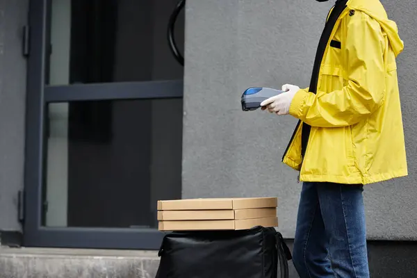 Eine Person mit schwarzer Maske bringt Essensbestellungen in ein Büro und steht neben einem großen Sack voller Lieferungen. — Stockfoto