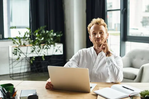 A redhead businessman in a white shirt sits at his desk, contemplating his project in a sleek office. — Stock Photo