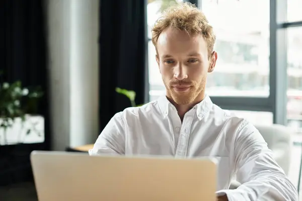 A redhead in a white shirt diligently working on a project at a stylish contemporary office setting. — Stock Photo