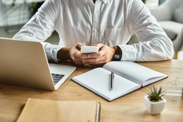 A professional man is focused on a mobile device while working in a sleek office. — Stock Photo