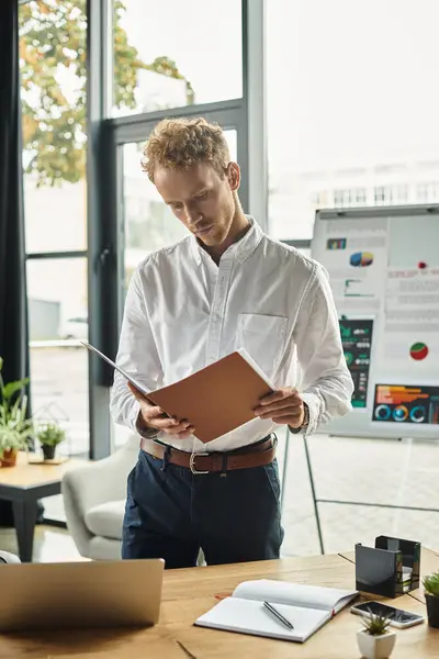A redhead businessman in a white shirt thoughtfully examines project documents while working in a sleek office. — Stock Photo