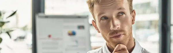 A redheaded businessman in a white shirt contemplates ideas while working in a contemporary office setting. — Stock Photo