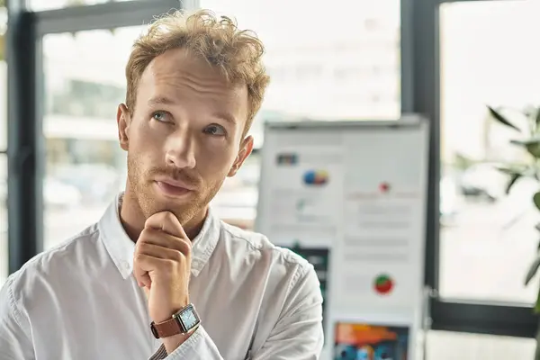 A focused businessman with red hair contemplates his next steps on a project in a contemporary office space. — Stock Photo