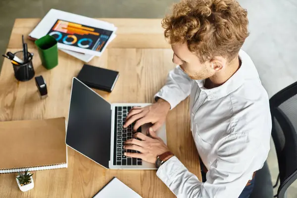 A dedicated redhead businessman works intently on a project, surrounded by modern office essentials. — Stock Photo