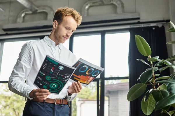 In a modern workspace, a redhead businessman examines documents while engaged in project planning. — Stock Photo