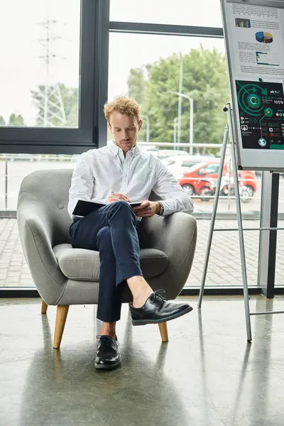 In a contemporary office, a redhead businessman in a white shirt diligently works on a project in a cozy chair. — Stock Photo