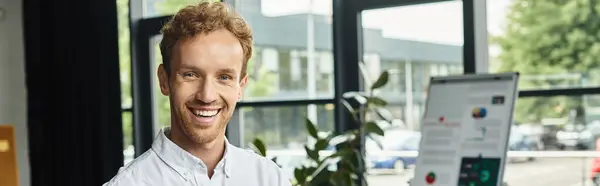 A focused redhead businessman in a white shirt collaborates on a project in a bright modern office. — Stock Photo